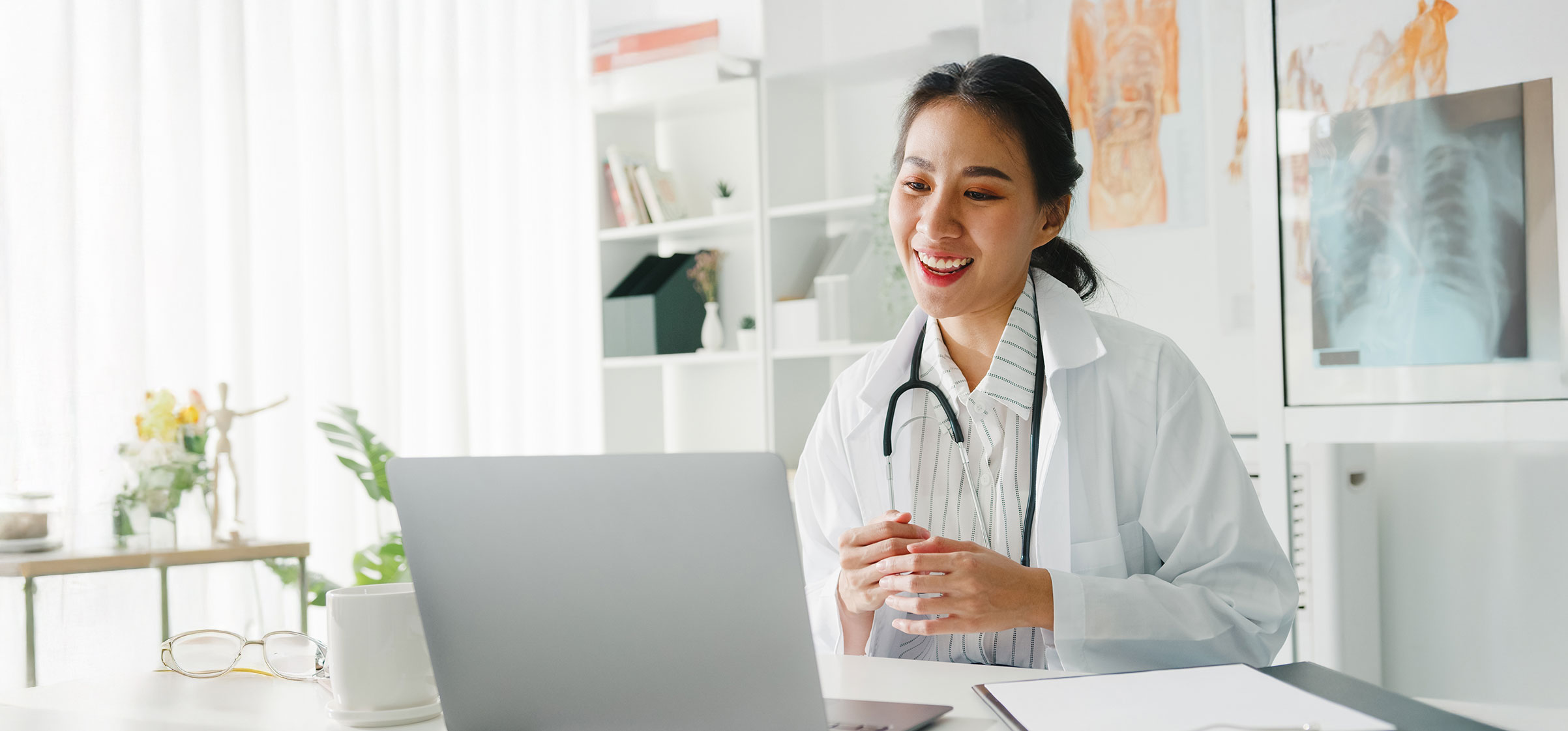 A young, professional female doctor uses a laptop for a video conference, providing personalized healthcare consultation to a patient.