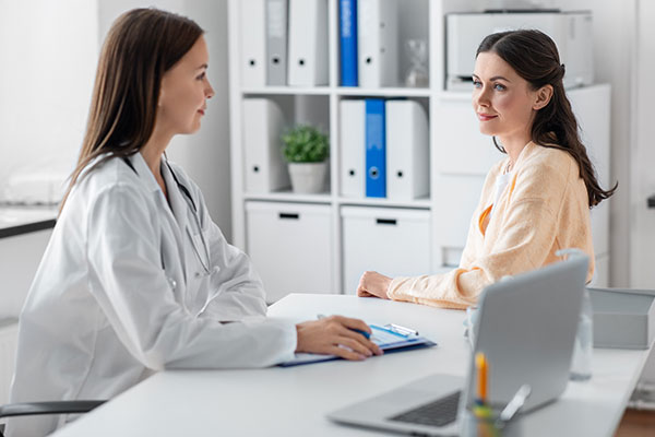 Doctor talks to young adult female patient in clinic.