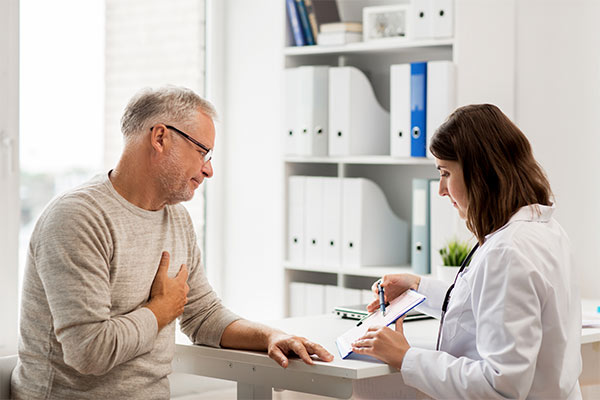 A man clutches his chest while talking to his heart doctor.