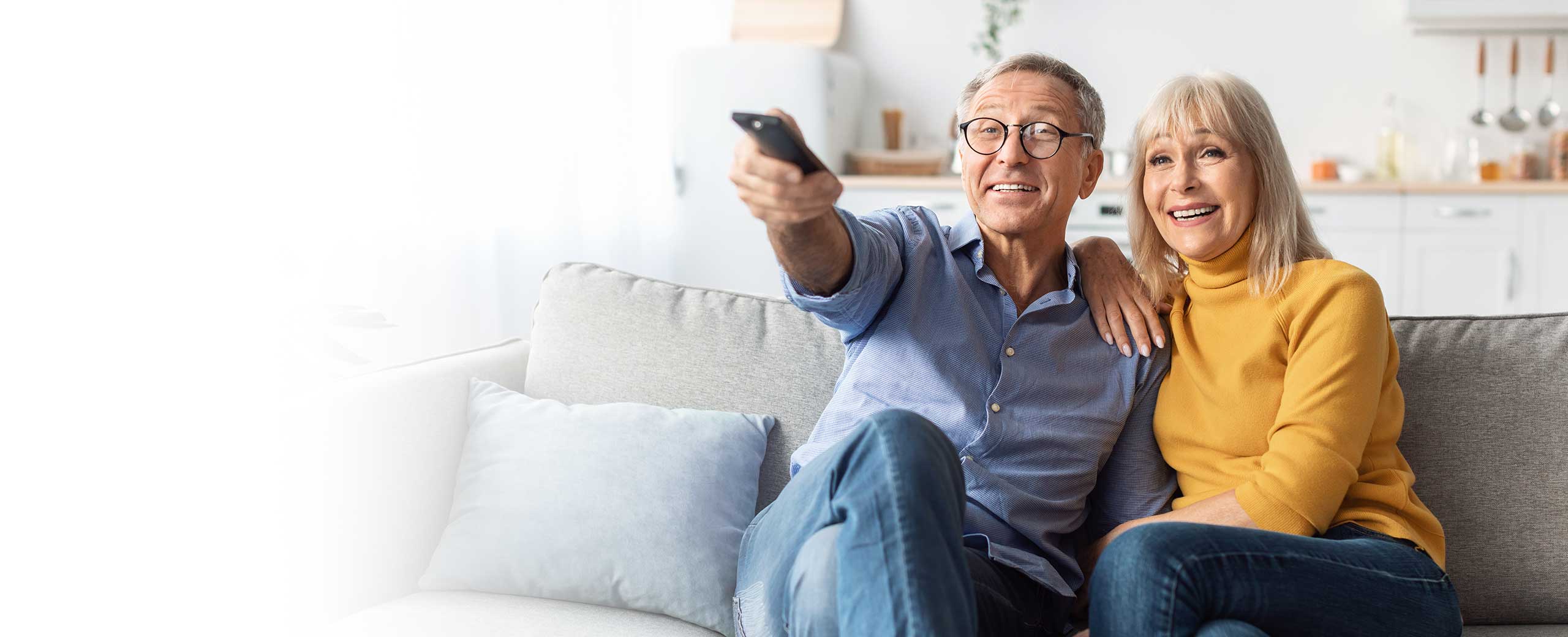 A couple watches tv on the couch.