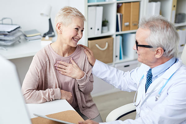 A woman smiles as a aortic specialist talks to her.