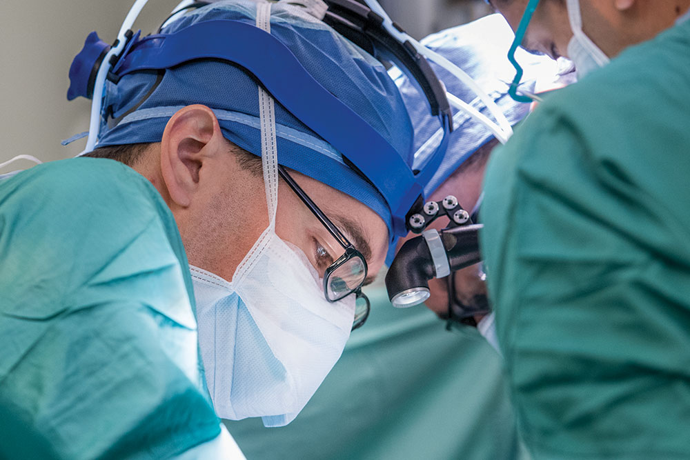 Dr. Kyle Cologne, wearing surgical mask and headlamp, performs surgery